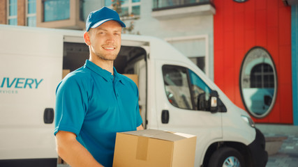 Handsome Courier Takes Cardboard Box Package out of Delivery Van Walks Through Modern Stylish...