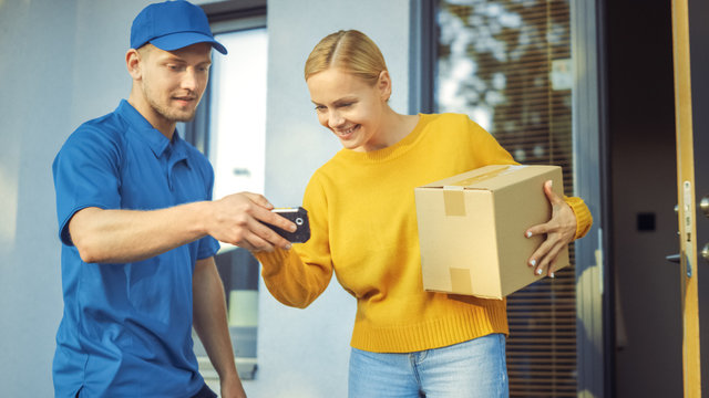Beautiful Young Woman Meets Delivery Man who Gives Her Cardboard Box Package, She Signs Electronic Signature POD Device. Courier Delivering Parcel in the Suburban Neighborhood. 