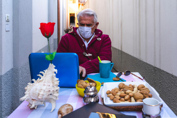 adult man is having breakfast while working on the computer outdoors