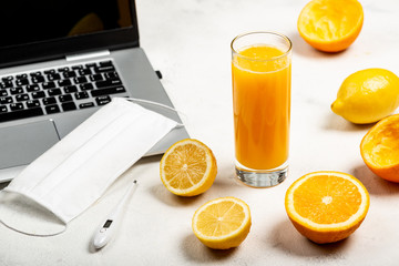 Things necessary for Online work and education in conditions of quarantine and freshly squeezed orange juice, citrus fruits for immunity boosting on the white background.