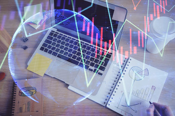 Double exposure of man's hands writing notes of stock market with forex chart.