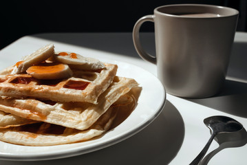 Cup of cocoa, toasts with jam and bananas on white plate