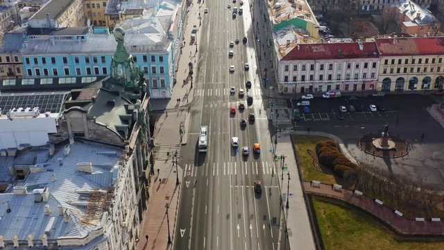 Fly above Nevsky avenue in St. Petersburg city center, aerial view in sunny morning. Traffic on road, few people on the sidewalk