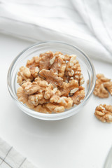  A pile of walnuts on a white background. Peeled walnuts in a glass dish.