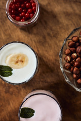 Yogurt with nuts on a wooden background. View from above. Summer food.