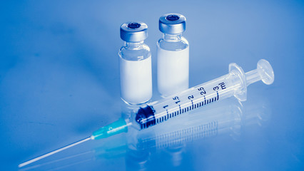 Vaccine vial dose flu shot drug needle syringe,medical concept . blue background. selection focus.Vaccine vial dose flu shot drug needle syringe,medical concept . blue background. selection focus.