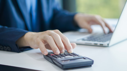 Businessman accountant using calculator and laptop for calculating finance on desk office. business financial accounting concept.