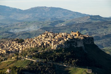 Obraz premium Sicilian landscape with the city of Calascibetta at nice sunset with shadows