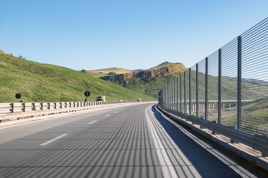 Sicilian highway A19 travelling through this beautiful Southern European island. The highway is equipped with crash barriers in a hilly part near Enna