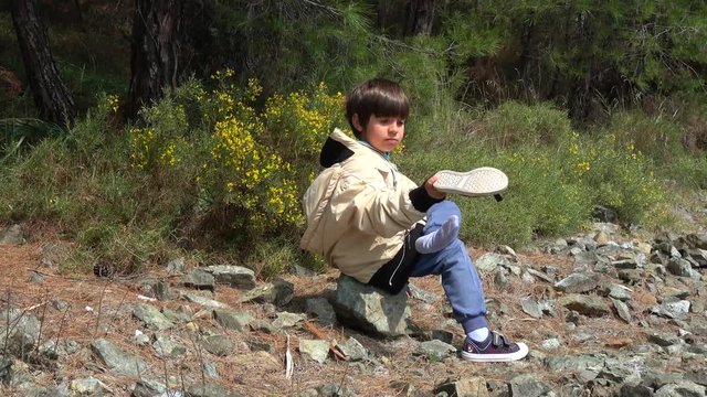 Fethiye, Turkey - 27d of March 2020: 4K Kid with a hole in his socks shakes out his shoes
