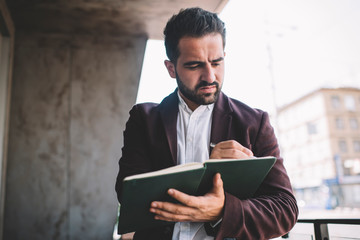 Serious businessman writing in planner on balcony