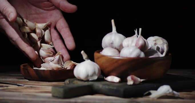 Male hand put cloves of garlic on a plate.