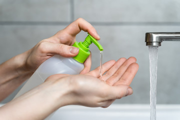 A woman uses a sanitizer with liquid soap to wash her hands. Hygiene concept to prevent the spread of the coronavirus epidemic