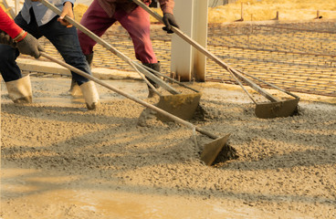 Three construction workers leveling concrete pavement.