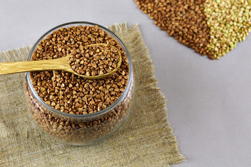 Dry buckwheat in a jar and wooden spoon