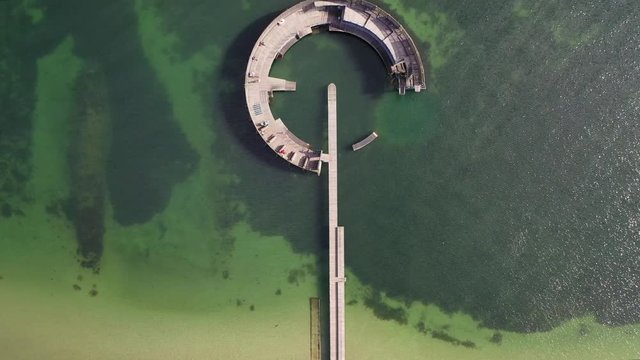 Unbelievable 4k flyover drone shot of modern pier over emerald green water in picturesque location near quant capital city