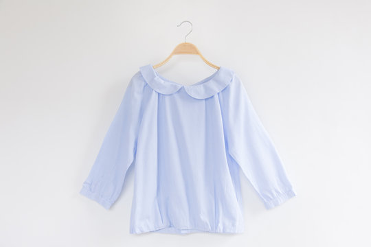 Close-up Of Blue Blouse Hanging Against Gray Background