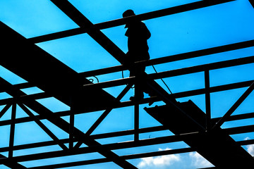 A man are installing the roofing sheet on Light steel Truss and Frame construction.