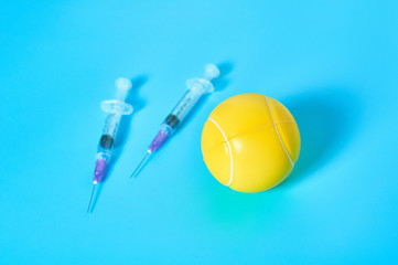 Tennis ball near syringe on blue background. Concept of doping in professional sport....