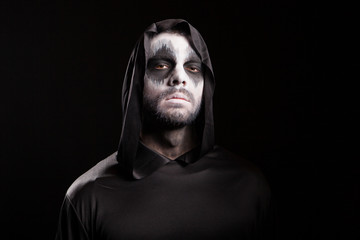 Fototapeta na wymiar Man with creepy face dressed up like grim reaper