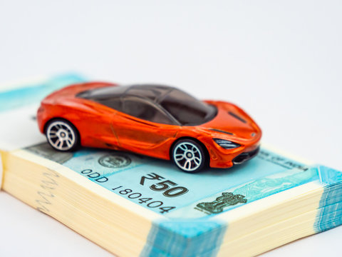 High angle close up shot of a toy car with money notes under it for wealth and lifestyle concept.