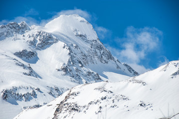 Fototapeta na wymiar Mountain peak with snowstorm clouds on the ridge. Alpine winter view