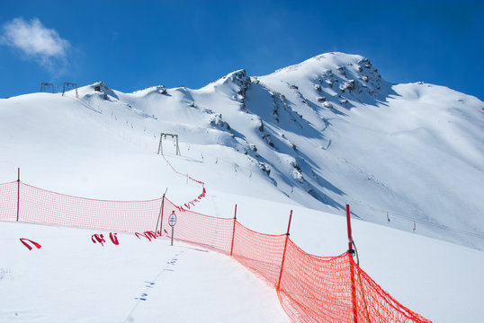 Avalanche warning sign and net fence in Caucasus mountains. Mount Cheget ln background.