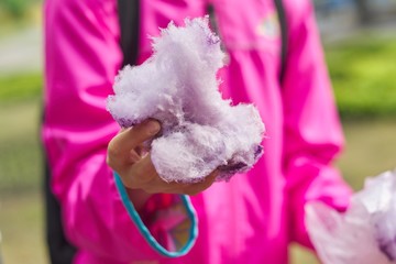 Girl child eating cotton candy floss, closeup sweet pink cloud