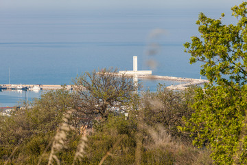 Christian crucifix on the hills over San Benedetto del Tronto, Marche , Italy. Pier in background with blue Adriatic sea