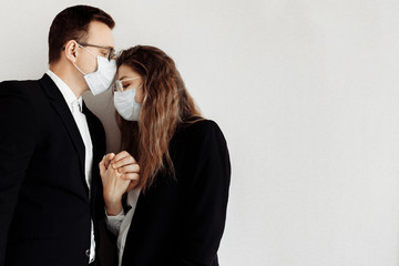 Couple in love in black suits wear medical face mask to protect each other from coronavirus. Stop pandemic 2020