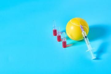 Tennis ball near syringe and ampoule on blue background. Concept of doping in professional sport. Rehabilitation, treatment after competition. Illegal medicaments using on tournament