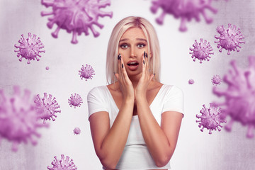 Scared young blonde girl. Portrait of a woman in white t-shirt coronavirus symbols around her. ...