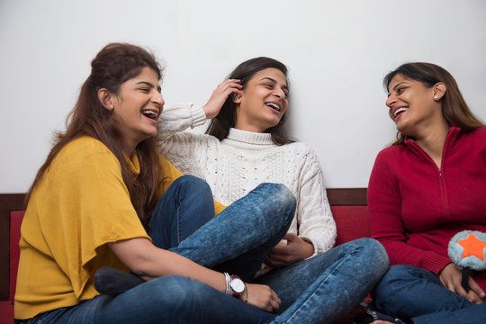 Three sisters laughing at each other. 
