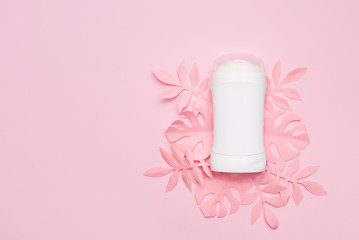 Deodorant and paper palm leaves on color pink background