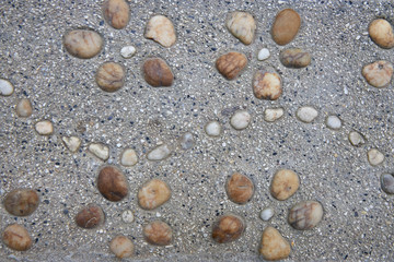 Pattern in the form of flowers composed of stones on asphalt as a background or backdrop