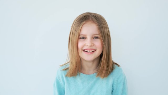 Lovely little girl smiling on white wall background