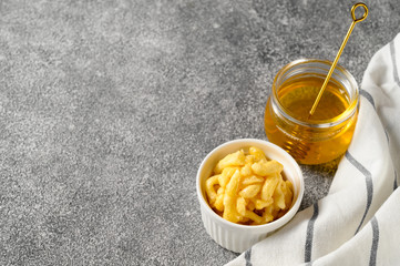 National food cuisine of the Middle East. White ramekin with chak chak and honey in a jar on a gray table. Horizontal orientation, copy space.