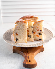 a dessert, sweet bread with dry fruits on a light plate, white background, raisins, apricots