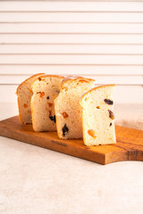 slices of bread, a dessert of the Easter bread, with raisins and apricots, light background, wooden board