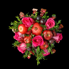 Bouquet of pomegranates, red apples, black plums and roses on a black background