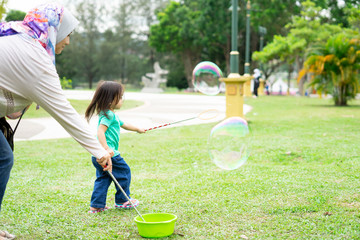 Lovely active little asian girl playing with soap bubble outdoor in the park