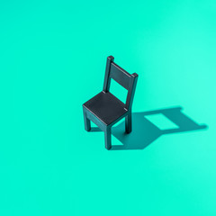 Concept Secretary`s Day, black chair on a mint background, symbol of work in the office, hard light, minimalism.