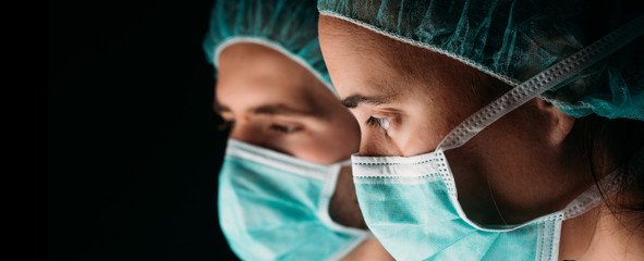 Woman and Man Doctor wearing protection face mask and against coronavirus on black background....