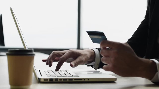 Man hand holding credit card and using laptop computer. Businessman or entrepreneur working at office. Online shopping, e-commerce, internet banking, finance concept