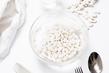 White beans soaked in water in glass bowl