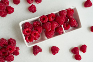 Bowl of delicious ripe raspberries on white background, top.