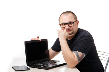 A man sits at a table with glasses and works on a laptop. On a white background.