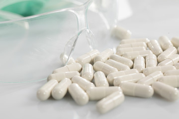 On the white table next to the protective glasses lie scattered tablets with a medicine for an infectious disease.