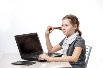 Cute schoolgirl sitting at a laptop on a white background