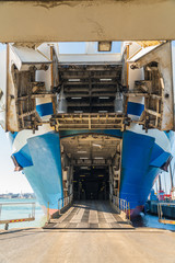The bow of a ship is open to be unloaded and loaded with lorries and other goods
